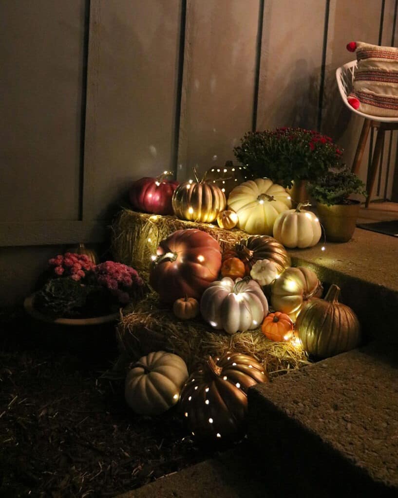 outdoor fall decor decor pumpkins, plants, and fairy lights at night