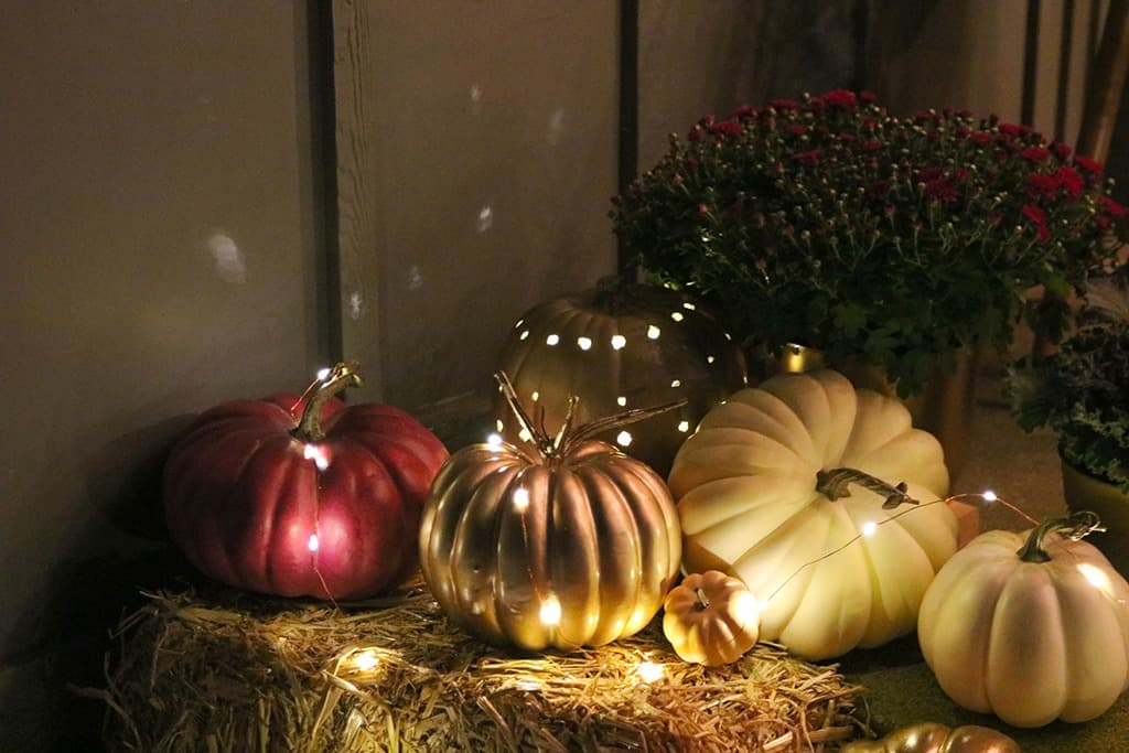 outdoor fall decor decor pumpkins, plants, and fairy lights at night