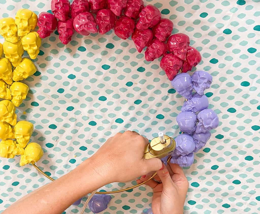 gluing spray painted skulls onto a halloween wreath - 4 different colors