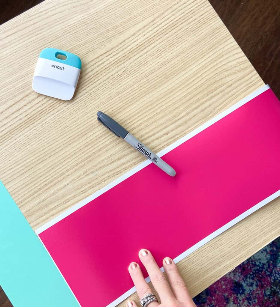 applying party pink vinyl to a table top design with a burnishing tool and fingers