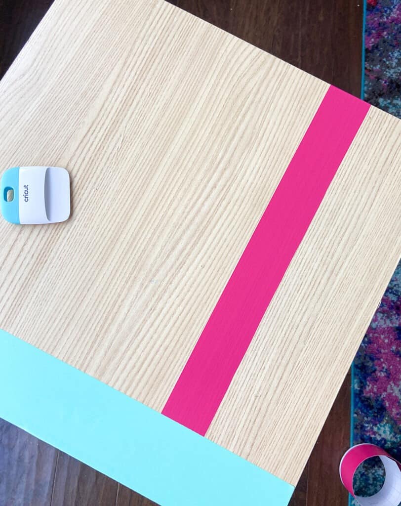 applying party pink vinyl to a table top design with a burnishing tool and fingers