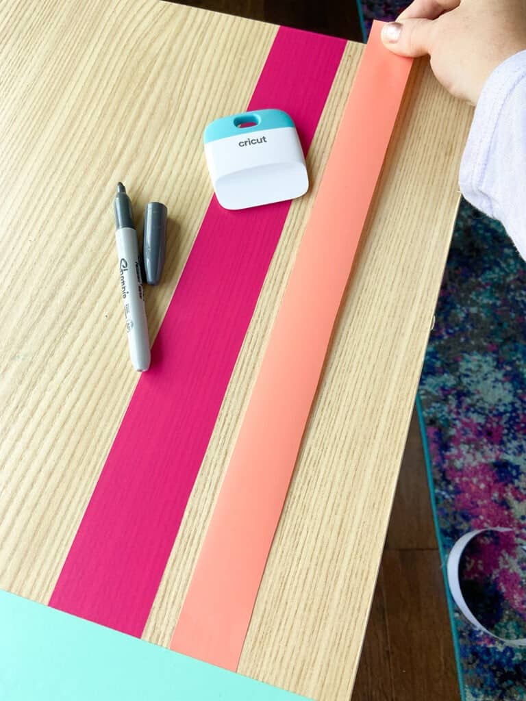 applying coral vinyl to a table top design with a burnishing tool and fingers