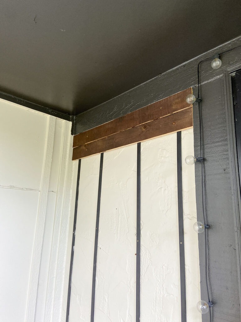 Installing wood slat to wall using a level, shim, and drill