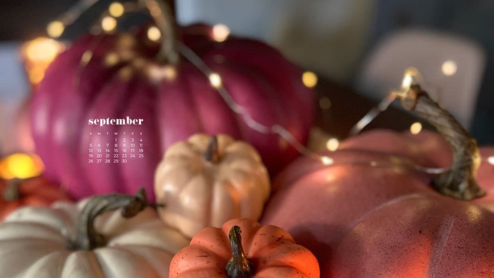 colorful stacked pumpkins on a table with fairy lights bokeh - pink, orange, coral, cream September 2021 - FREE wallpaper calendars in Sunday and Monday starts + no-calendar options. 35 designs for both desktop and smart phones!