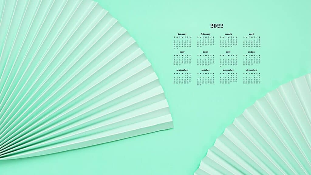 green paper fans on green background with 2022 full-year calendar for your desktop 