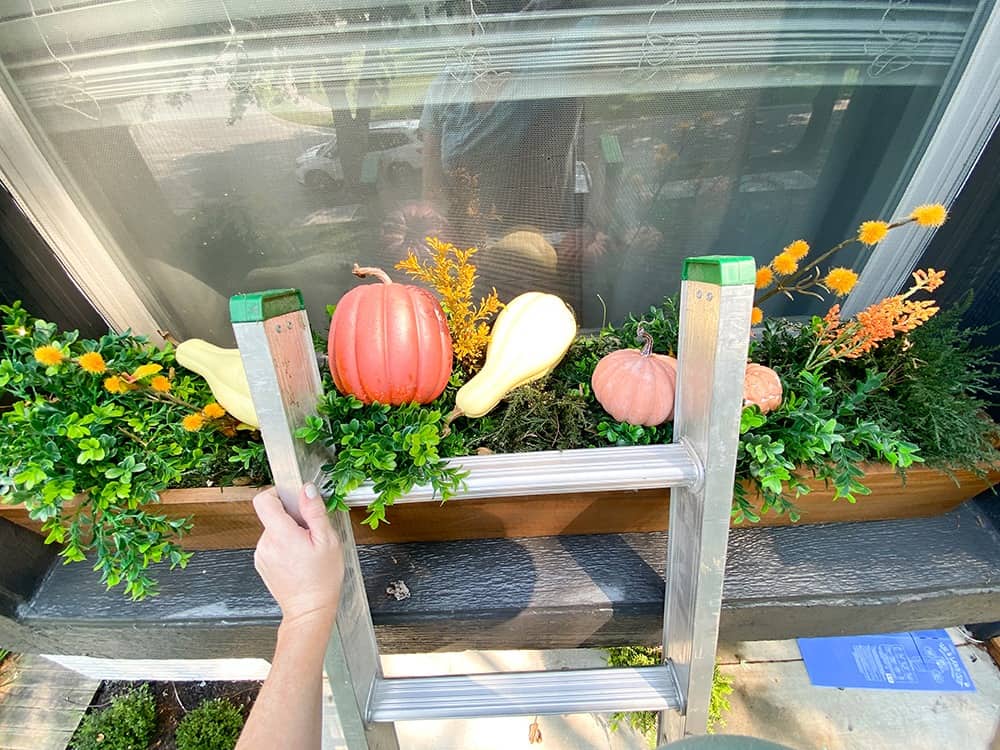 fall window box decor faux greenery, pumpkins, and fairy lights