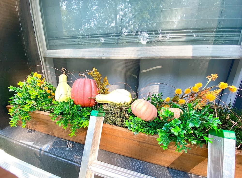 fall window box decor faux greenery, pumpkins, and fairy lights
