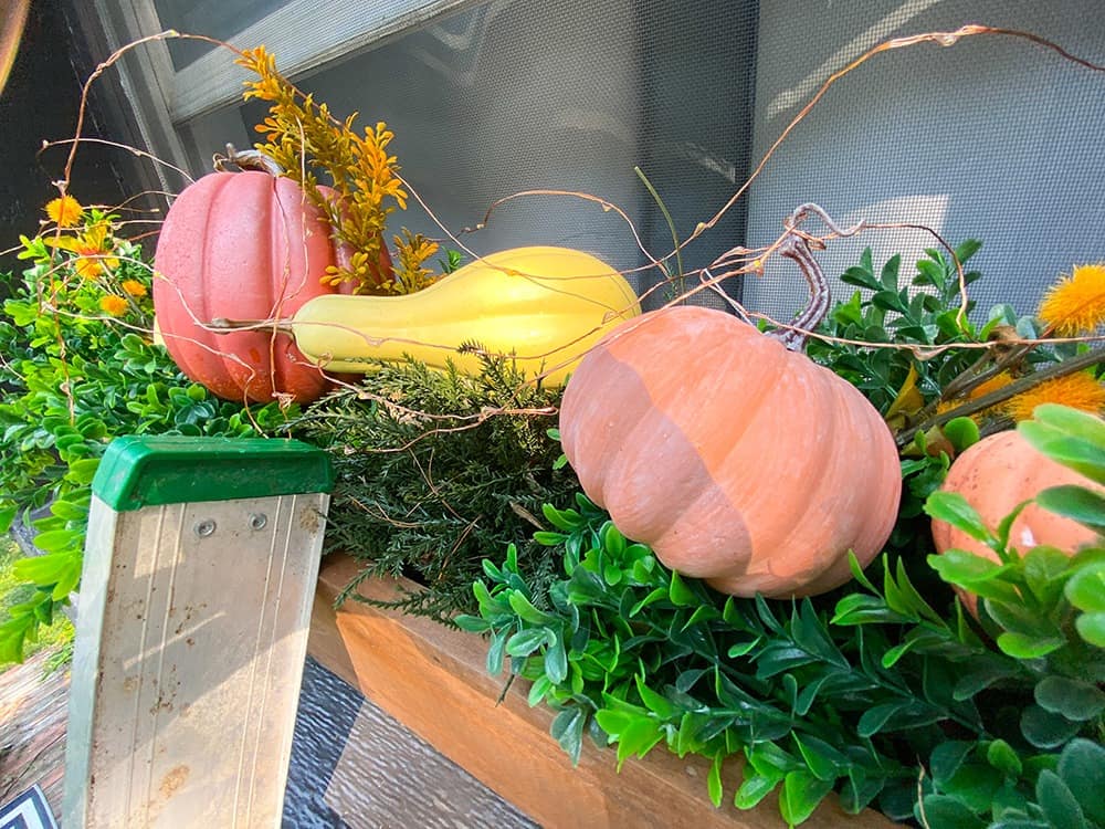 fall window box decor faux greenery, pumpkins, and fairy lights