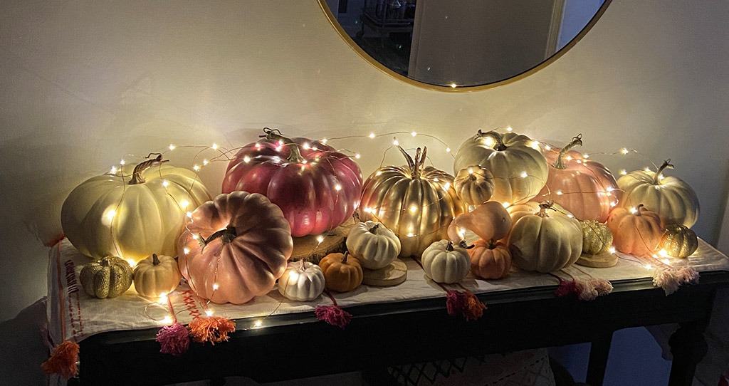 Fall entryway with lots of colorful pumpkins and fairy lights