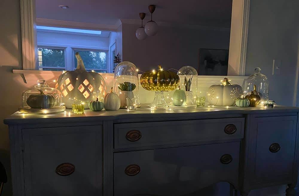 faux pumpkins, plants, glass cloches, candles, and fairy lights on a vintage cabinet top - easy fall decorating ideas!