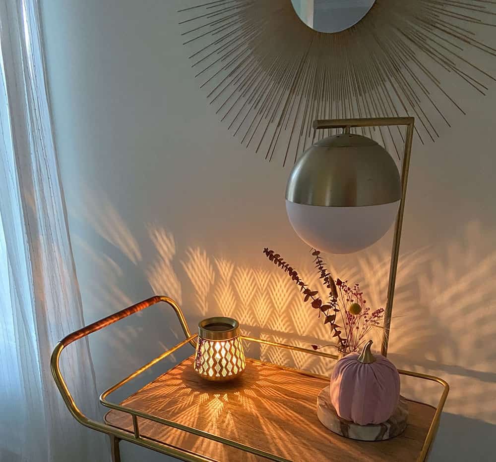 Gold and wood decorated bar cart with a faux pink pumpkin, dried florals in a vase, and a wax warmer that scatters light across the wall. fall decorating ideas!