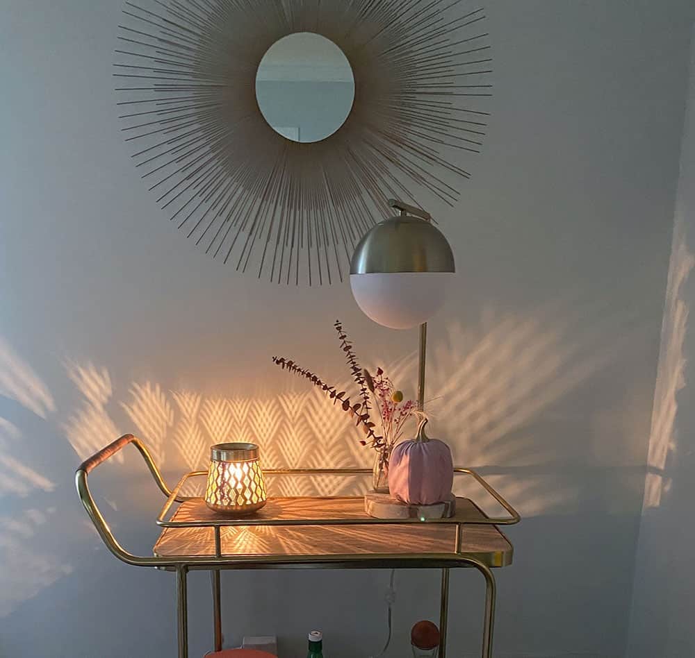 Gold and wood decorated bar cart with a faux pink pumpkin, dried florals in a vase, and a wax warmer that scatters light across the wall. fall decorating ideas!