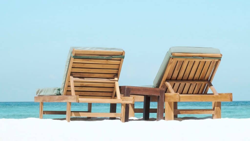 2 wooden beach chairs looking a a beautiful beach