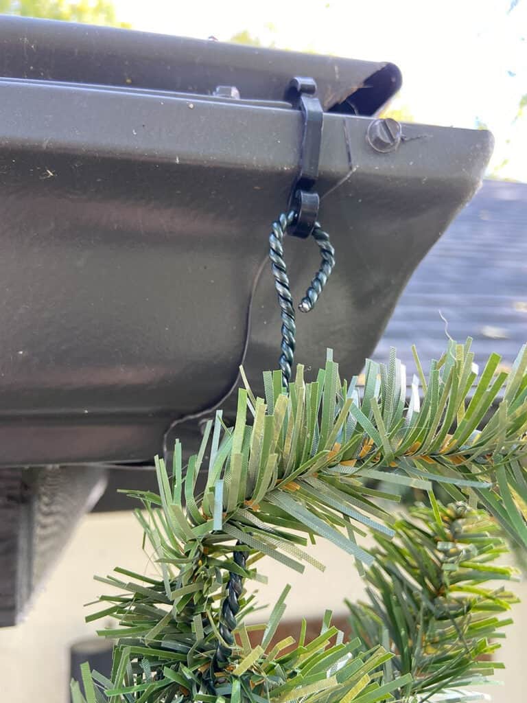 adding fairy lights and garland to gutters on porch and front of house