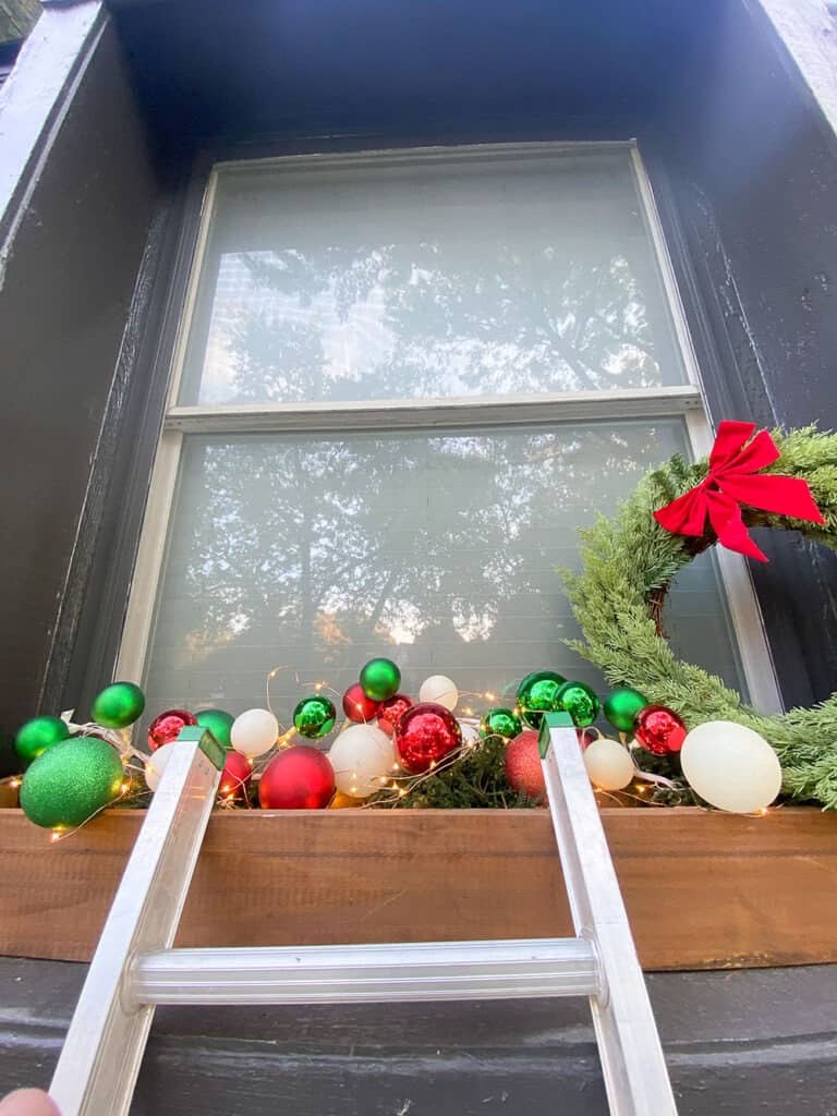 outdoor holiday window box decor using ornament garland and a classic wreath