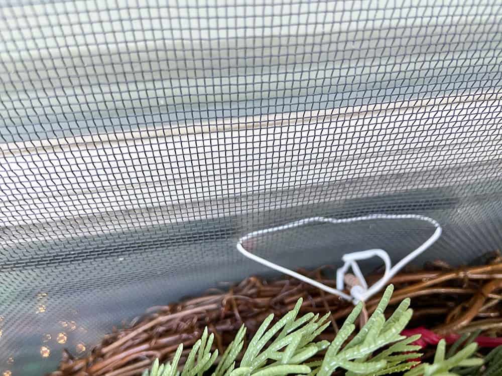 hanging a holiday wreath on a window screen