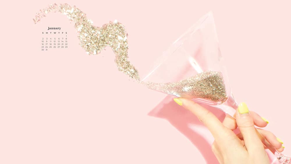 January 2022 pink background with hand holding champagne glass of gold glitter