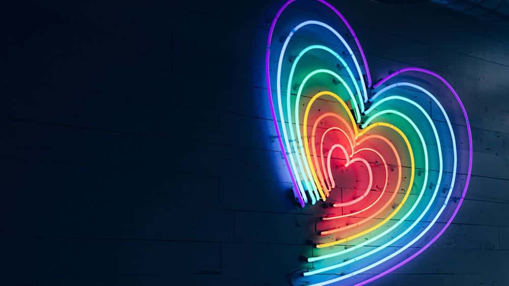 neon rainbow heart on navy wall background