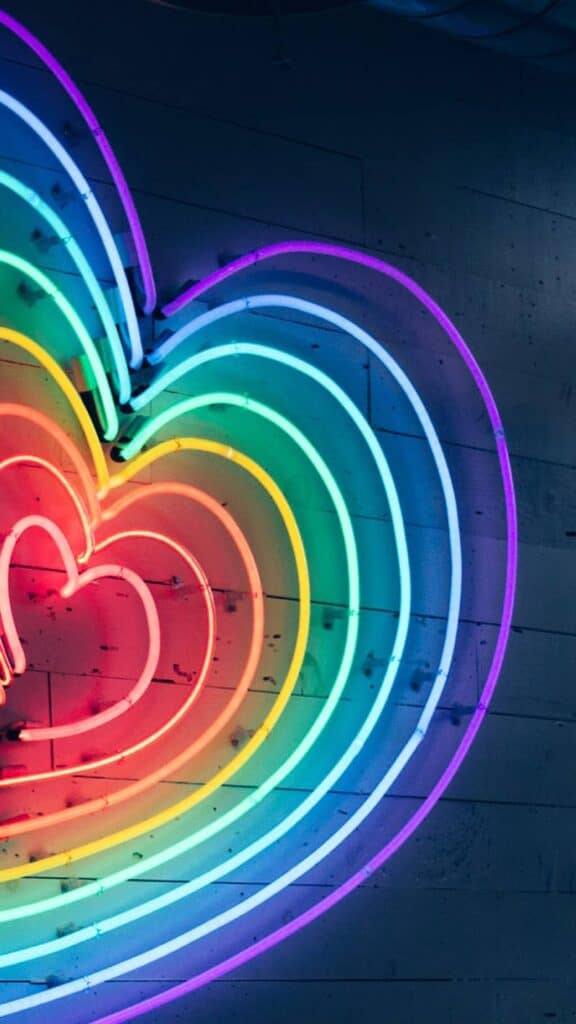 neon rainbow heart on navy wall background