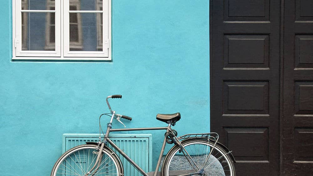 bike propped against turquoise building and black doors