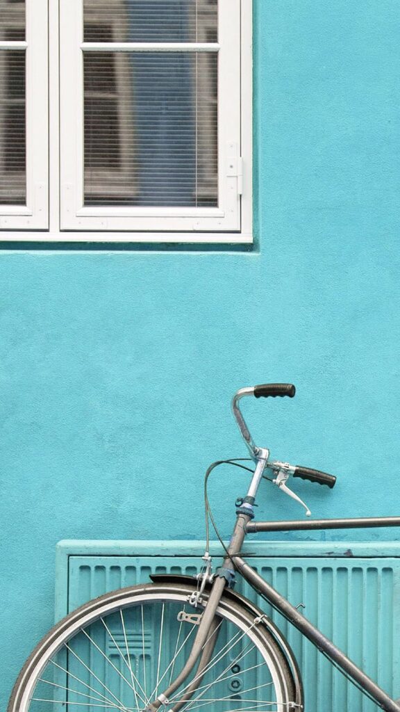 bike propped against turquoise building and black doors