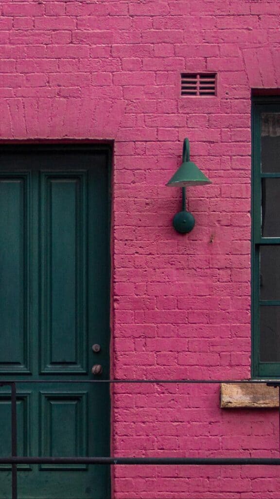 hot pink painted brownstone flat with cool old green doors and lights