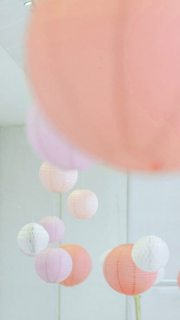 pink, purple, peach, white, and coral round paper lanterns hanging in a white room