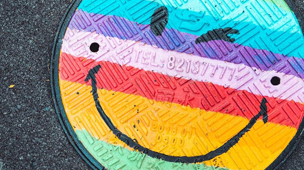 rainbow painted smiley face man hole drain cover