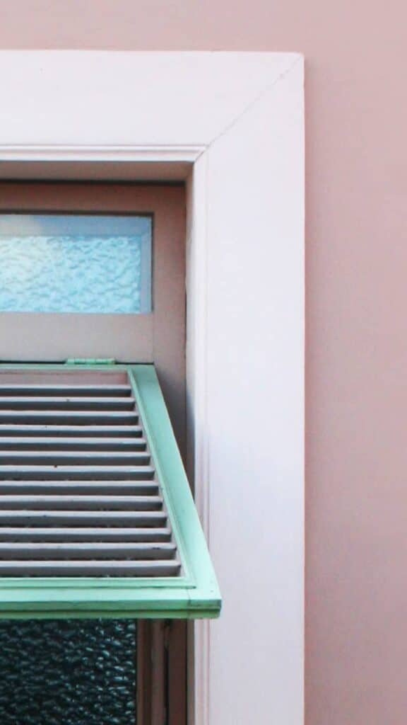 pink wall with green window shutters