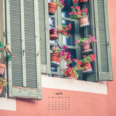 pink building with green shutters and lots of plants with april 2022 calendar