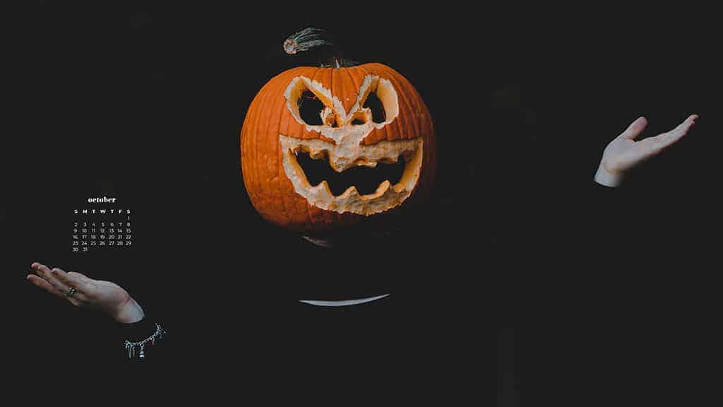 person wearing a pumpkin head on a black background October 2022 wallpapers – FREE calendars in Sunday & Monday starts + no-calendar designs. 55 beautiful options for desktop & smart phones!