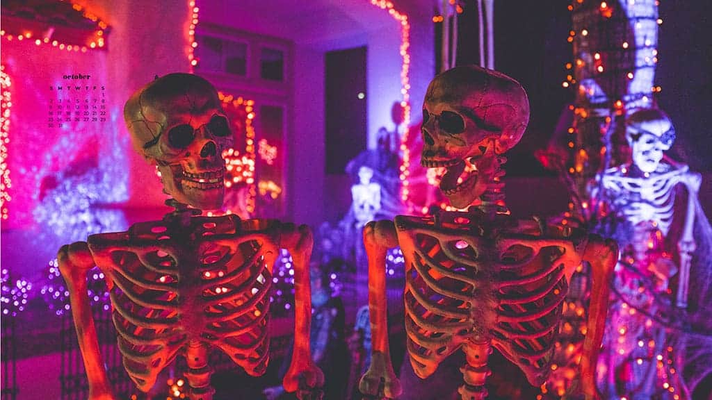 fake halloween skeletons in front of a halloween party with colorful party lights October 2022 wallpapers – FREE calendars in Sunday & Monday starts + no-calendar designs. 55 beautiful options for desktop & smart phones!