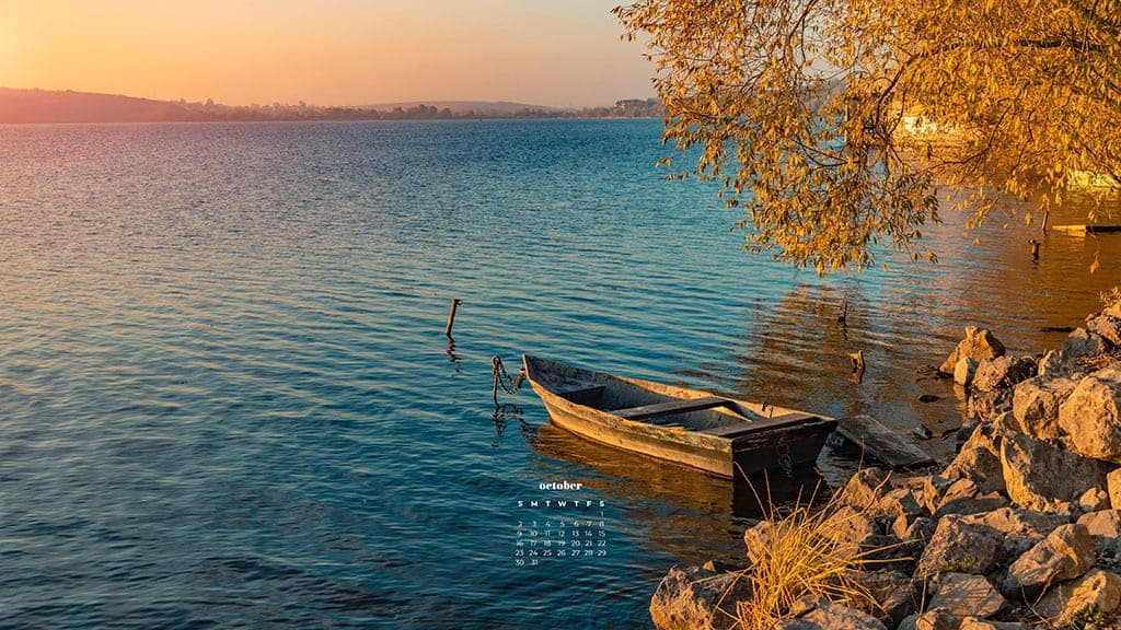 a small boat on the water next to a yellow tree on an october day October 2022 wallpapers – FREE calendars in Sunday & Monday starts + no-calendar designs. 55 beautiful options for desktop & smart phones!