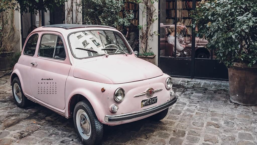 small vintage pink car on a cobblestone street